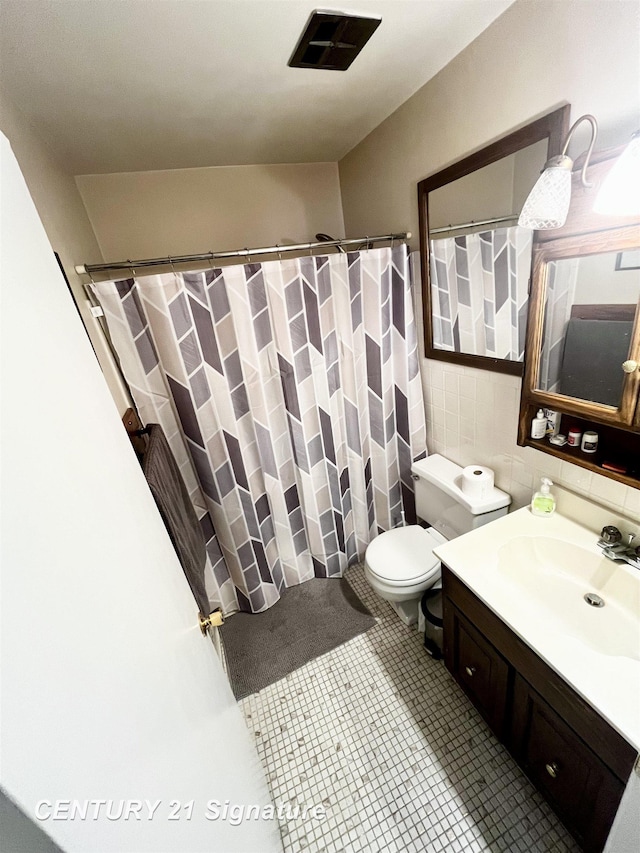 bathroom with toilet, tile walls, vanity, curtained shower, and tile patterned flooring