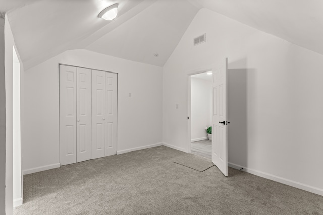 unfurnished bedroom with lofted ceiling, carpet floors, and a closet