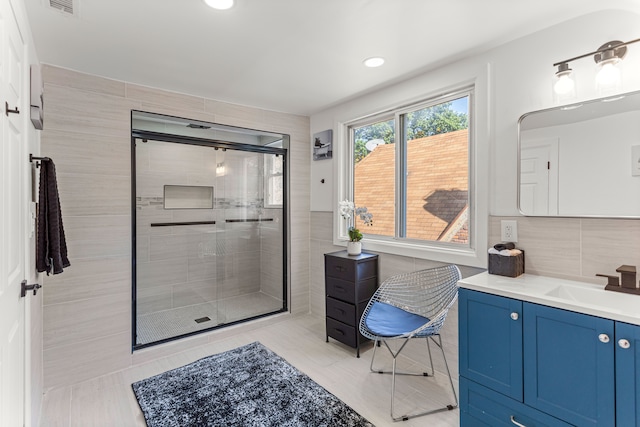 bathroom featuring tasteful backsplash, vanity, a shower with door, and tile patterned floors