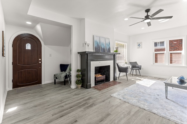 living room featuring ceiling fan, a fireplace, and light hardwood / wood-style floors