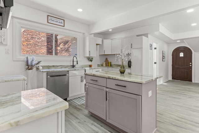 kitchen with gray cabinets, dishwasher, a center island, light stone countertops, and light wood-type flooring