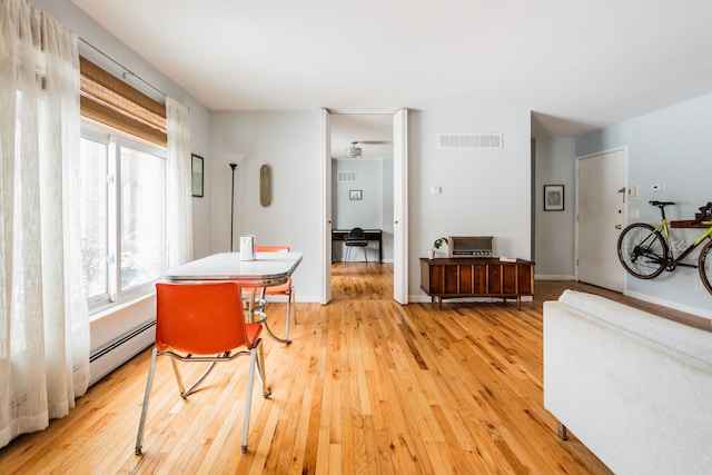 dining area featuring a baseboard heating unit and light wood-type flooring