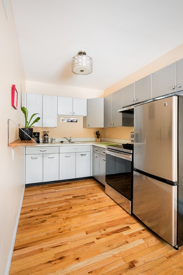 kitchen featuring stainless steel appliances, sink, light hardwood / wood-style floors, and gray cabinetry