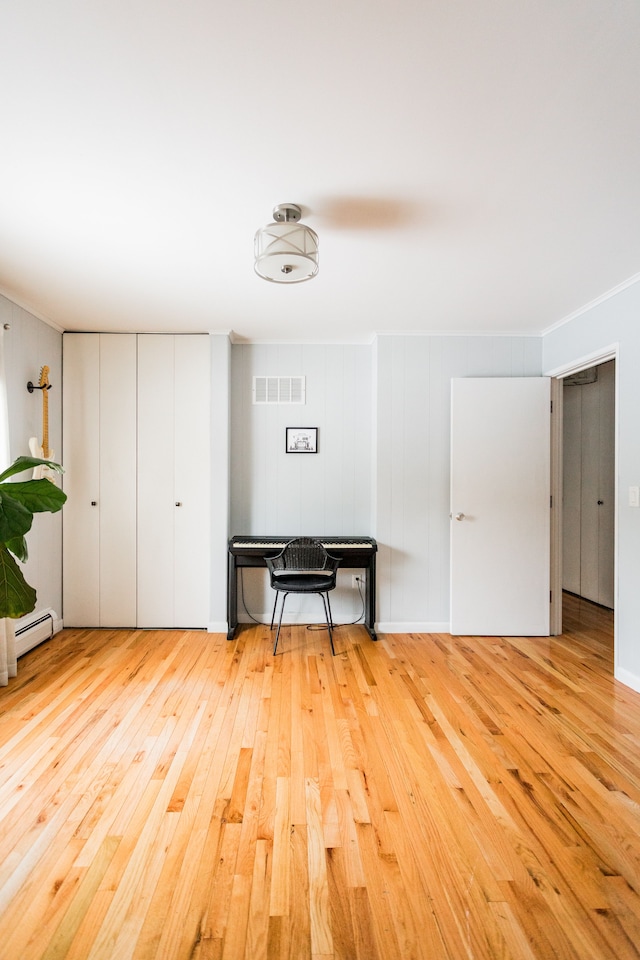 interior space featuring baseboard heating and light hardwood / wood-style floors