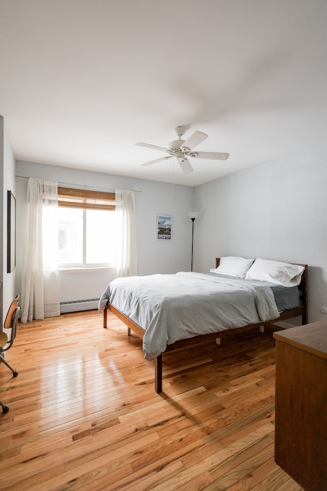 bedroom featuring a baseboard radiator, light hardwood / wood-style floors, and ceiling fan