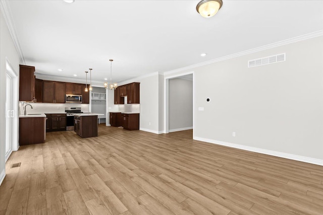 kitchen with sink, decorative light fixtures, ornamental molding, a kitchen island, and stainless steel appliances