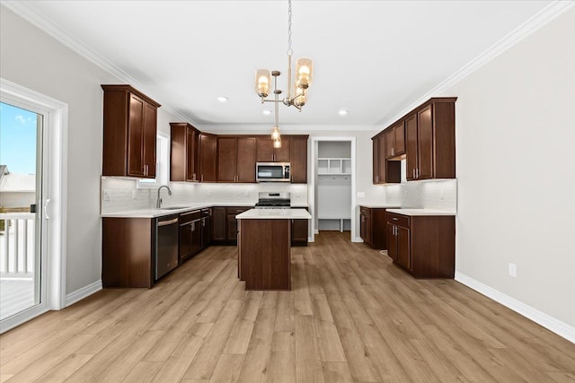 kitchen featuring sink, decorative light fixtures, dark brown cabinets, appliances with stainless steel finishes, and a kitchen island