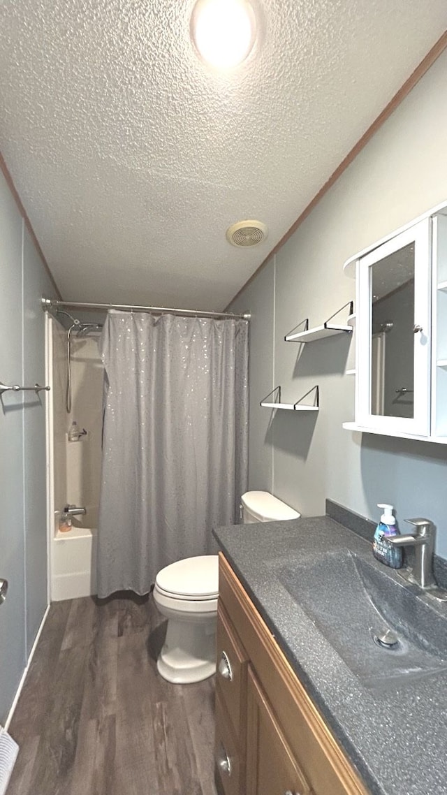 full bathroom with hardwood / wood-style flooring, toilet, a textured ceiling, shower / bath combo with shower curtain, and vanity