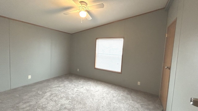 carpeted empty room with ceiling fan, ornamental molding, and lofted ceiling