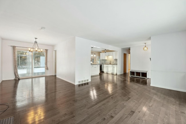 unfurnished living room featuring dark wood-type flooring, a chandelier, and sink