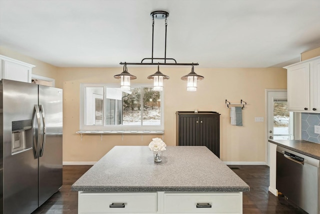 kitchen with appliances with stainless steel finishes, decorative light fixtures, a kitchen island, and white cabinets