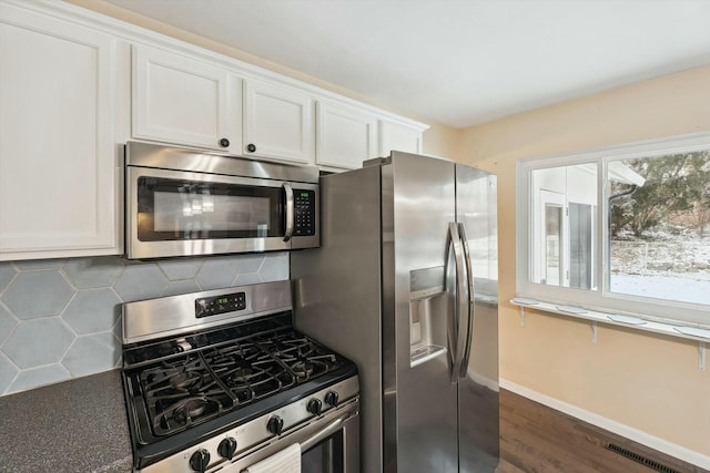 kitchen with white cabinetry, stainless steel appliances, and backsplash