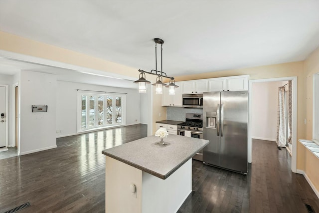 kitchen with white cabinetry, tasteful backsplash, hanging light fixtures, appliances with stainless steel finishes, and a kitchen island