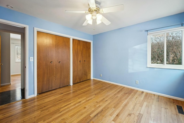 unfurnished bedroom featuring two closets, ceiling fan, and light hardwood / wood-style flooring