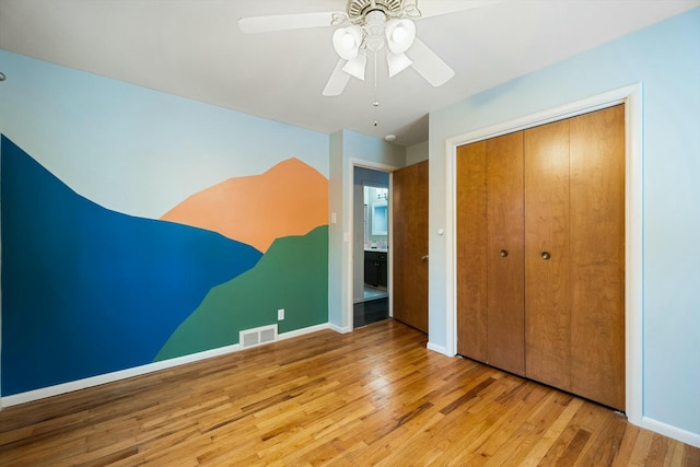 unfurnished bedroom featuring ceiling fan, a closet, and light wood-type flooring