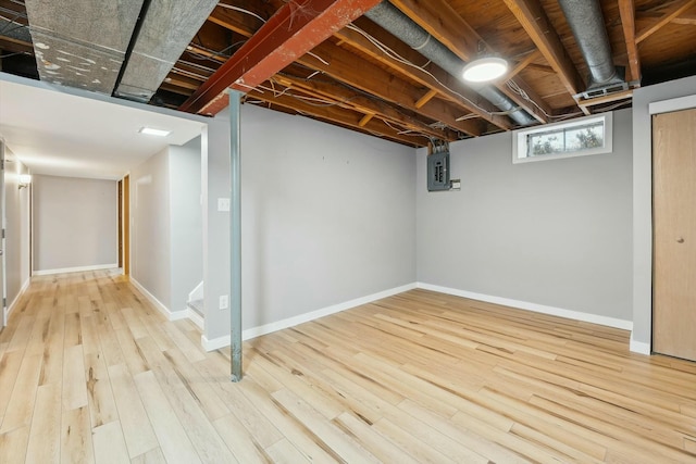 basement featuring electric panel and light hardwood / wood-style floors