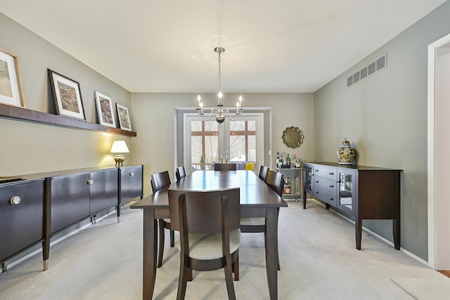 dining area with french doors, a chandelier, and light carpet