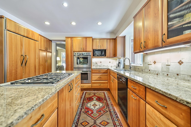 kitchen featuring light stone counters, sink, decorative backsplash, and black appliances