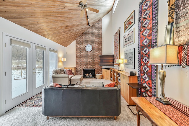 living room featuring high vaulted ceiling, a fireplace, light colored carpet, ceiling fan, and wood ceiling