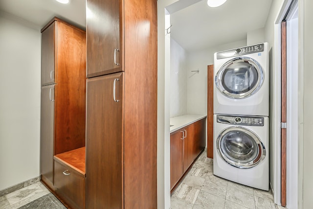 washroom featuring cabinets and stacked washer and clothes dryer