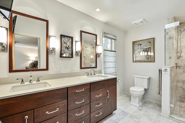 bathroom with vanity, tiled shower, and toilet