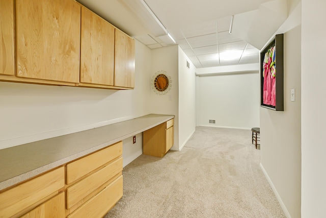 carpeted office featuring a paneled ceiling and built in desk