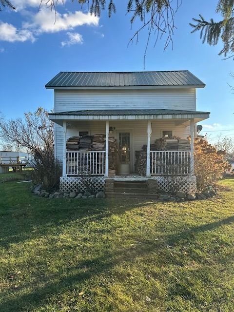 rear view of house featuring a lawn and a porch