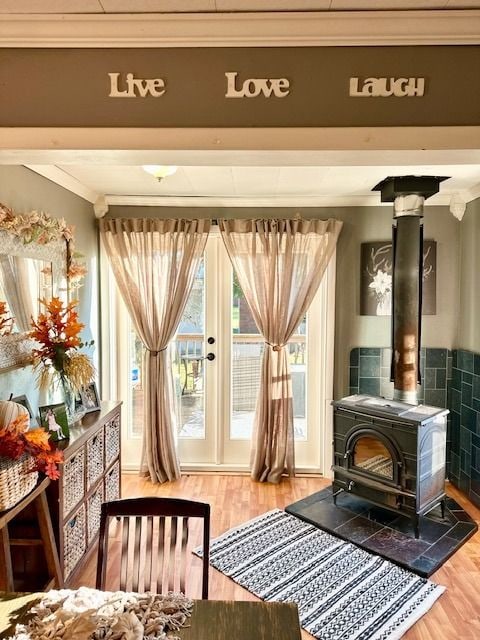 sitting room with hardwood / wood-style flooring, ornamental molding, and a wood stove