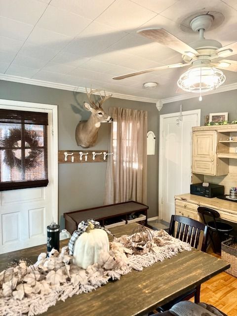 dining space with crown molding, wood-type flooring, and ceiling fan