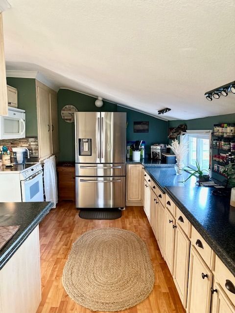 kitchen with vaulted ceiling, white appliances, light hardwood / wood-style floors, and backsplash