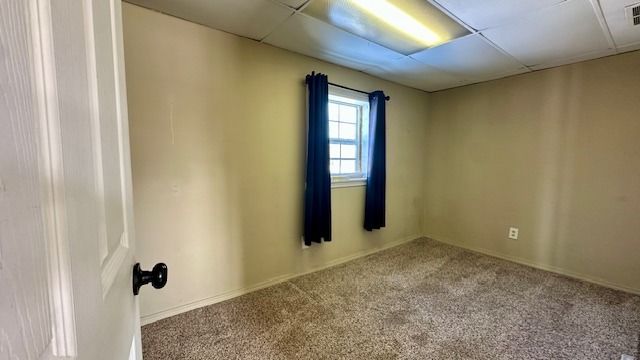 carpeted spare room featuring a drop ceiling