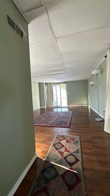 hallway with a paneled ceiling and dark hardwood / wood-style floors