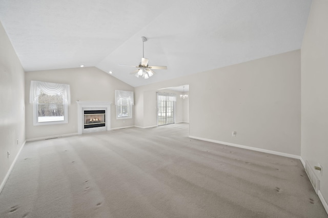 unfurnished living room featuring lofted ceiling, ceiling fan with notable chandelier, and light carpet