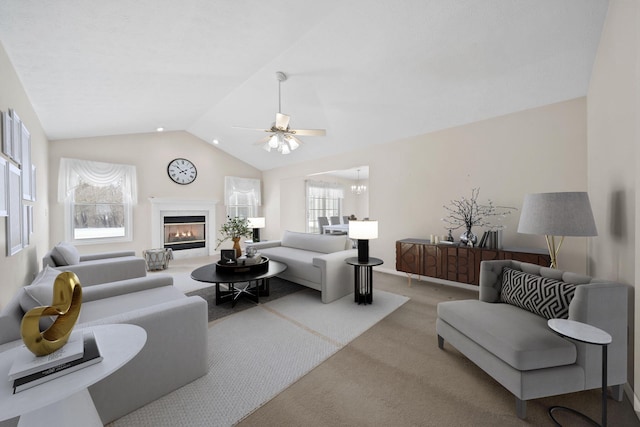 carpeted living room with ceiling fan and vaulted ceiling