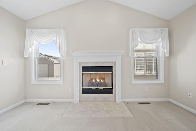 unfurnished living room with light colored carpet, vaulted ceiling, and a tile fireplace