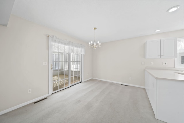 unfurnished dining area with light colored carpet and a notable chandelier