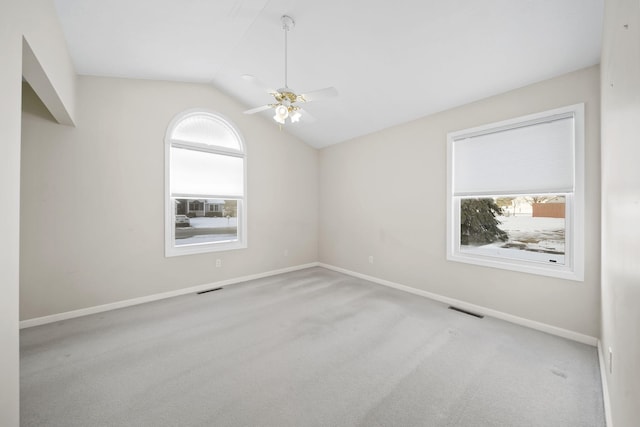 carpeted empty room with lofted ceiling, plenty of natural light, and ceiling fan