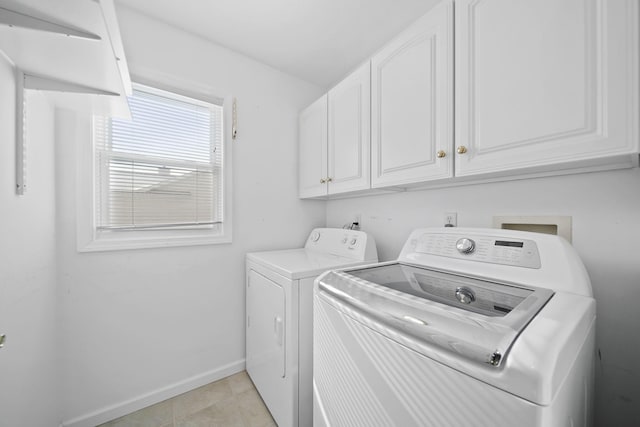 laundry room with light tile patterned flooring, cabinets, and washing machine and dryer