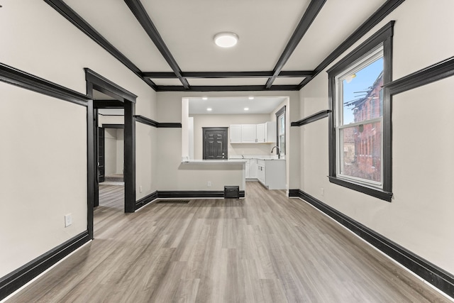 unfurnished living room with coffered ceiling, sink, beam ceiling, and light hardwood / wood-style flooring