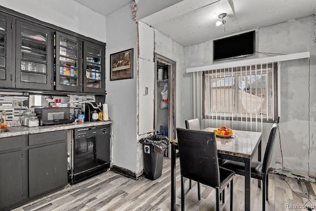 kitchen with tasteful backsplash, light hardwood / wood-style floors, and black appliances