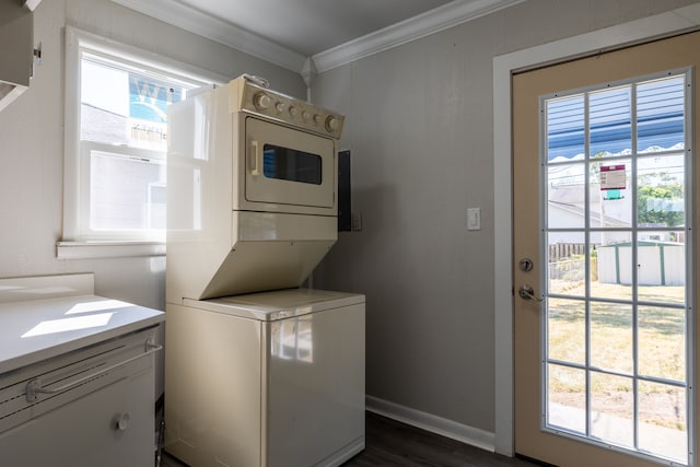 clothes washing area featuring dark hardwood / wood-style floors, a healthy amount of sunlight, stacked washer / drying machine, and ornamental molding