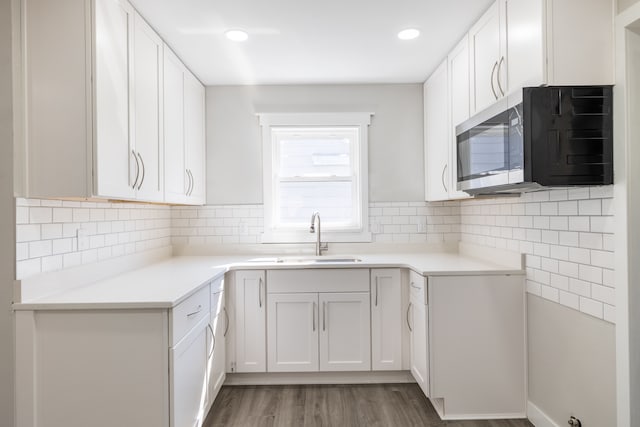 kitchen featuring white cabinetry, wood-type flooring, sink, and backsplash