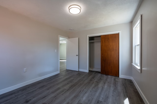 unfurnished bedroom with dark wood-type flooring, a closet, and a textured ceiling