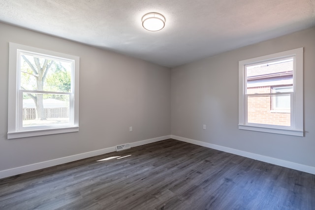 empty room with dark wood-type flooring and a textured ceiling