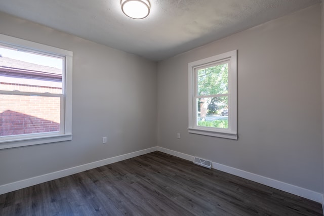 spare room featuring dark wood-type flooring and a textured ceiling