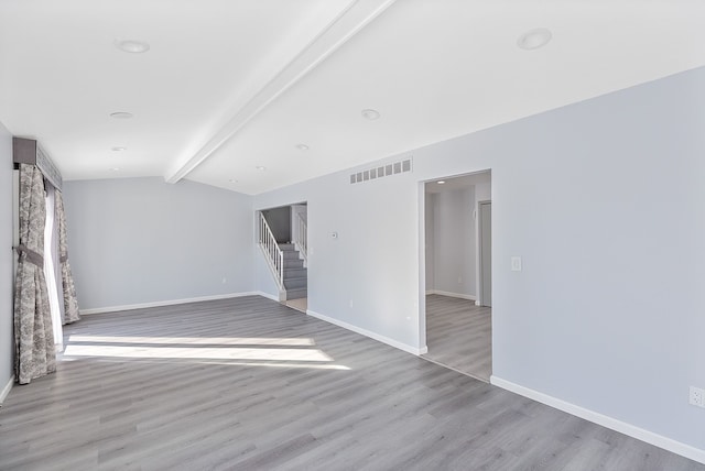 spare room featuring lofted ceiling with beams and light hardwood / wood-style floors