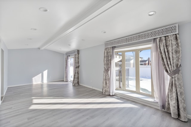 spare room featuring lofted ceiling with beams, plenty of natural light, and light hardwood / wood-style floors