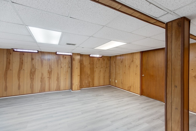 basement with a drop ceiling and light hardwood / wood-style flooring