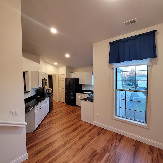 kitchen featuring white cabinetry, light hardwood / wood-style floors, and black fridge