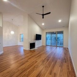 unfurnished living room with wood-type flooring, ceiling fan, and vaulted ceiling